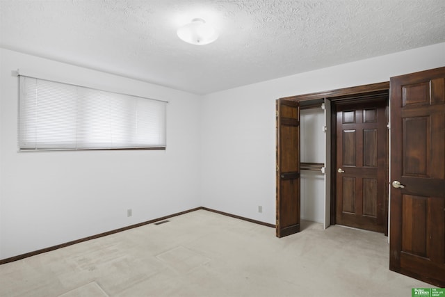 unfurnished room with light colored carpet and a textured ceiling