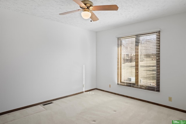 carpeted spare room featuring ceiling fan and a textured ceiling