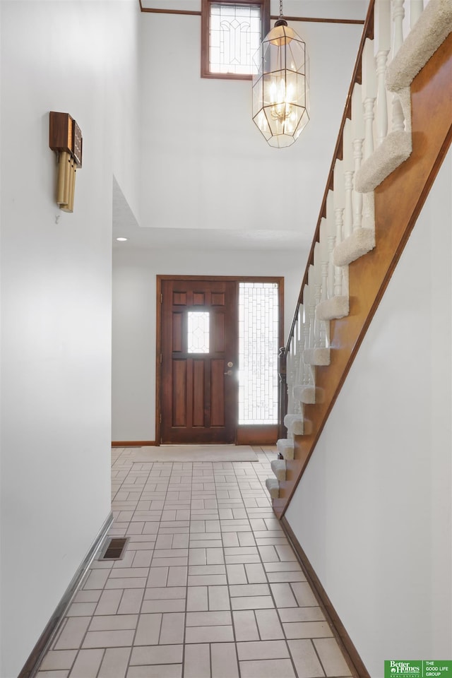 foyer with a notable chandelier, plenty of natural light, and a towering ceiling