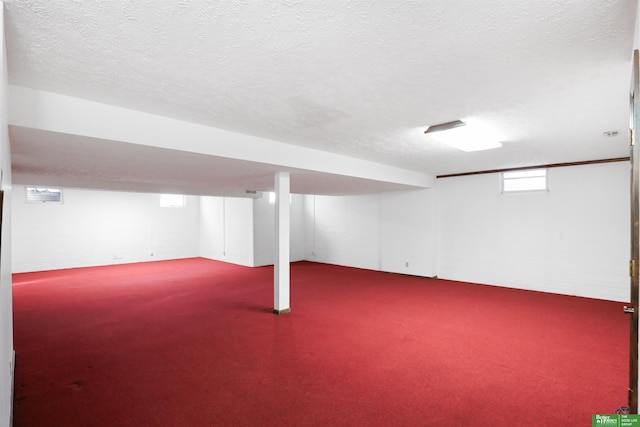 basement featuring a textured ceiling, brick wall, and carpet