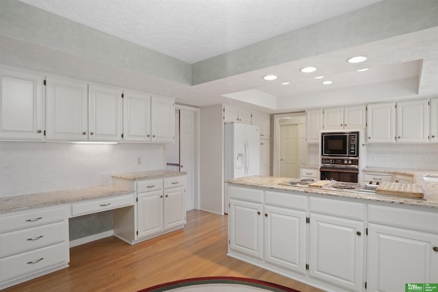 kitchen featuring black appliances, a tray ceiling, and white cabinetry