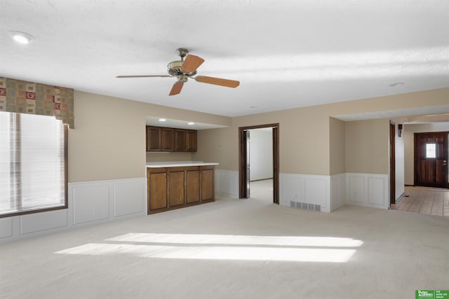 unfurnished living room featuring light carpet and ceiling fan