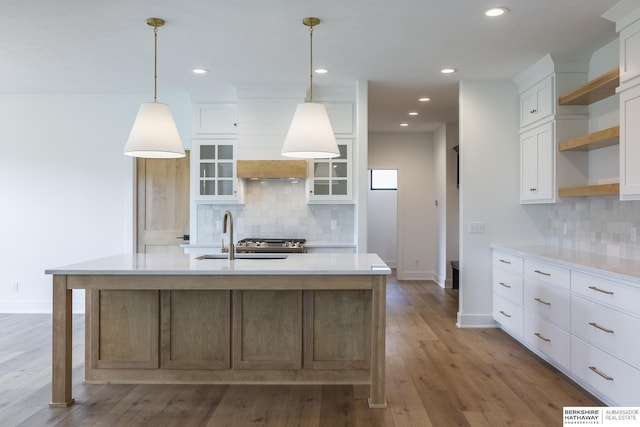 kitchen with white cabinetry, a kitchen island with sink, and hanging light fixtures