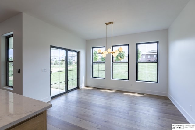 unfurnished dining area with an inviting chandelier and hardwood / wood-style floors