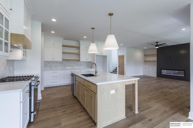 kitchen with stainless steel appliances, a kitchen island with sink, white cabinets, and sink