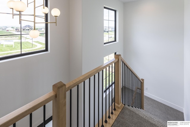 stairway with carpet floors and a chandelier