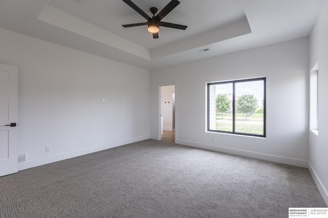 carpeted empty room featuring ceiling fan and a tray ceiling