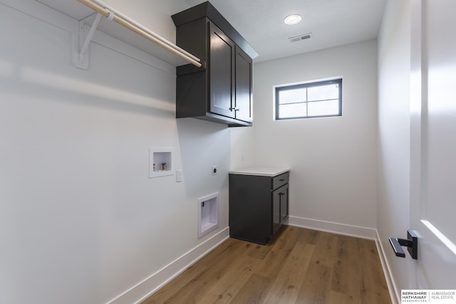 washroom with hardwood / wood-style floors, hookup for a washing machine, electric dryer hookup, and cabinets