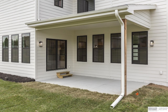 property entrance featuring a lawn and a patio area