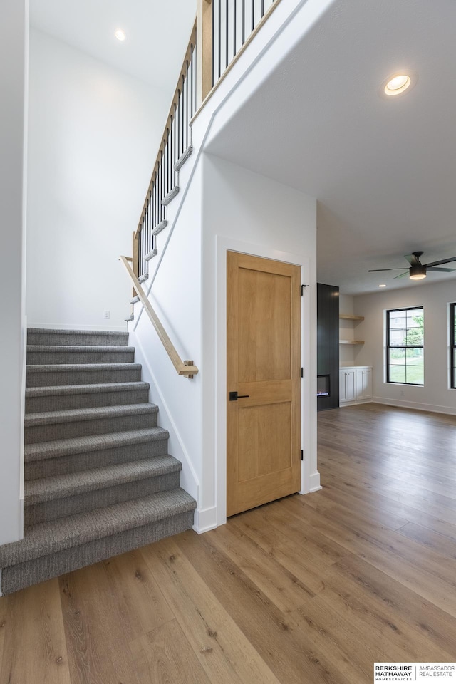 staircase with ceiling fan and hardwood / wood-style floors