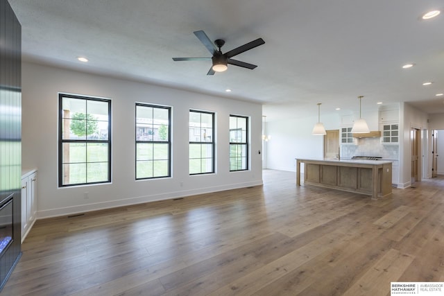 unfurnished living room featuring ceiling fan and light hardwood / wood-style flooring