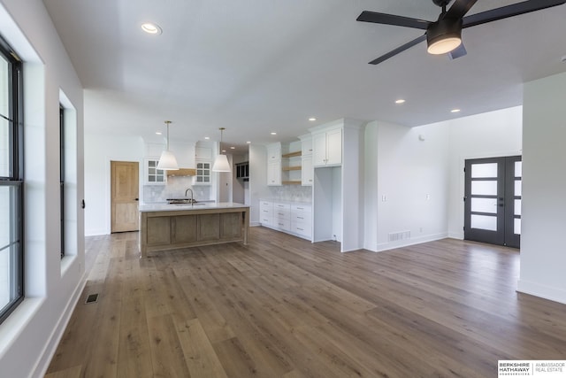 kitchen with a spacious island, white cabinets, decorative backsplash, hanging light fixtures, and ceiling fan