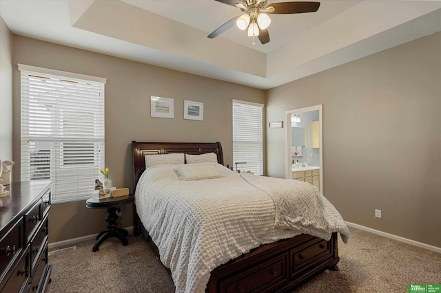 bedroom with ceiling fan, carpet, connected bathroom, and a tray ceiling