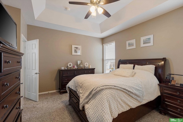 carpeted bedroom with ceiling fan and a raised ceiling