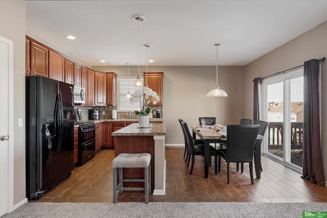 kitchen featuring tasteful backsplash, a center island, black appliances, a breakfast bar, and hanging light fixtures