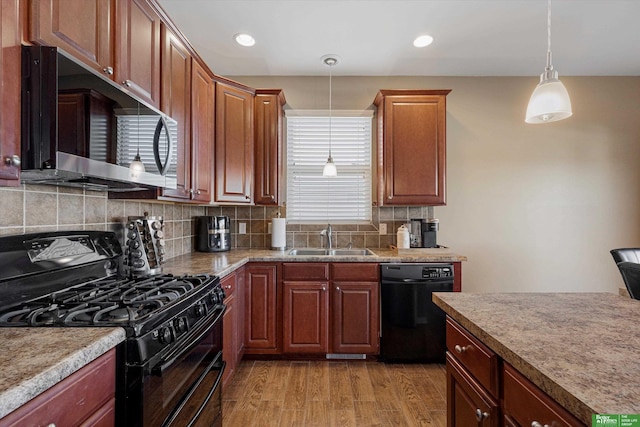 kitchen featuring backsplash, light hardwood / wood-style floors, black appliances, sink, and hanging light fixtures