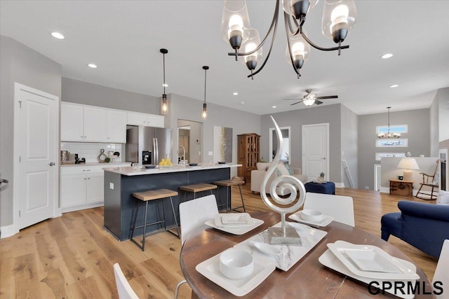 dining room featuring sink, ceiling fan with notable chandelier, and light hardwood / wood-style flooring