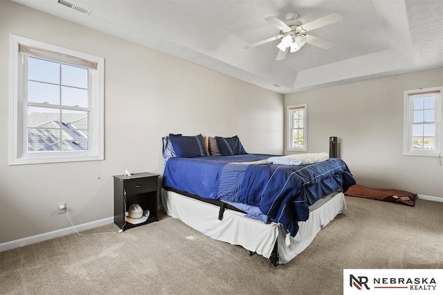 bedroom with ceiling fan, a tray ceiling, and carpet flooring