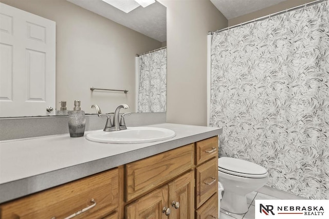 bathroom featuring toilet, a skylight, a textured ceiling, and vanity