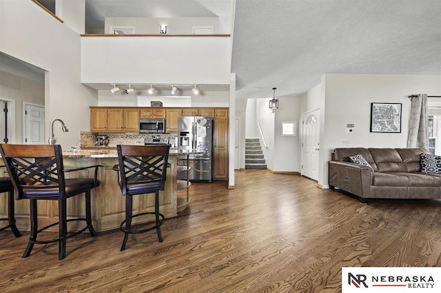 kitchen with tasteful backsplash, a breakfast bar, stainless steel appliances, a textured ceiling, and dark hardwood / wood-style flooring