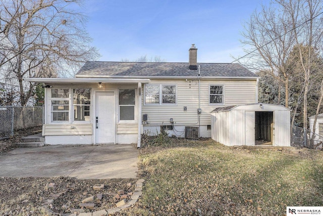 rear view of property featuring central AC, a lawn, a storage unit, and a patio