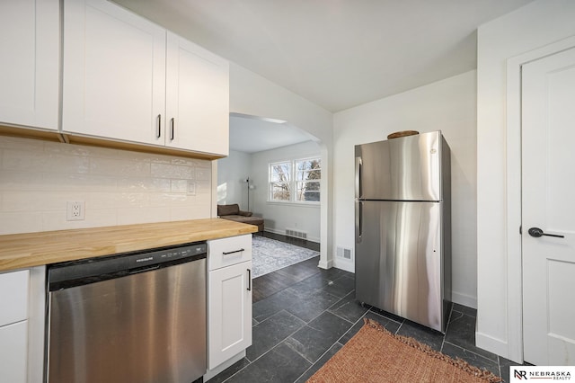 kitchen featuring tasteful backsplash, white cabinets, wood counters, and stainless steel appliances