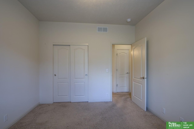 unfurnished bedroom with a textured ceiling, a closet, and light carpet