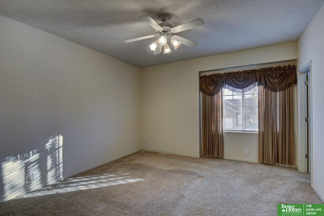 spare room with ceiling fan, light colored carpet, and a textured ceiling