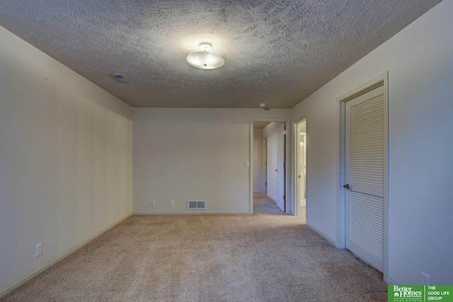 carpeted empty room with a textured ceiling