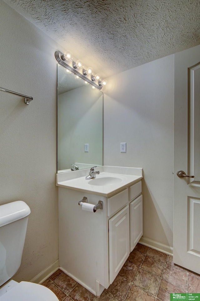 bathroom featuring toilet, vanity, and a textured ceiling