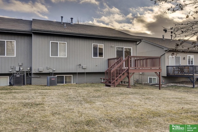 back house at dusk featuring a wooden deck, cooling unit, and a yard