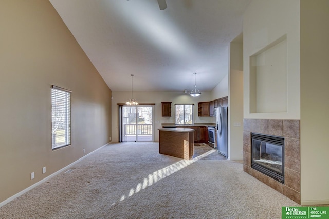 kitchen featuring a kitchen island, decorative light fixtures, light carpet, a fireplace, and stainless steel refrigerator