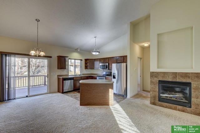 kitchen with appliances with stainless steel finishes, a center island, light carpet, and a tiled fireplace