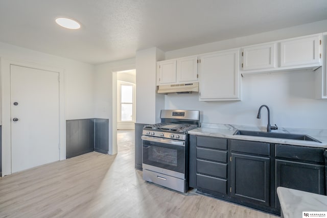 kitchen featuring light hardwood / wood-style floors, sink, white cabinetry, and stainless steel gas range oven