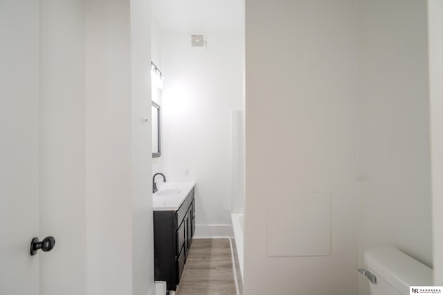 bathroom with toilet, a bathtub, wood-type flooring, and vanity