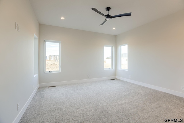 empty room featuring ceiling fan, a wealth of natural light, and light carpet