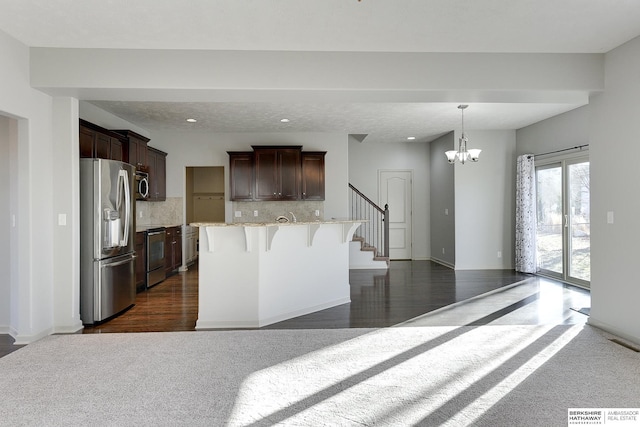 kitchen with stainless steel appliances, tasteful backsplash, a chandelier, a breakfast bar, and a center island