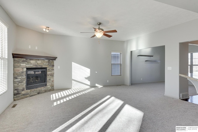 living room with ceiling fan, carpet, and a stone fireplace