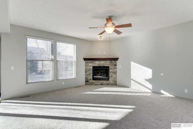 unfurnished living room featuring ceiling fan, carpet floors, and a stone fireplace