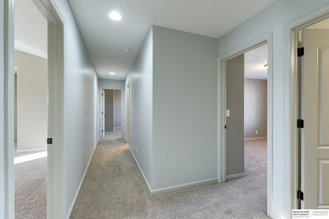 hallway with light carpet and a textured ceiling