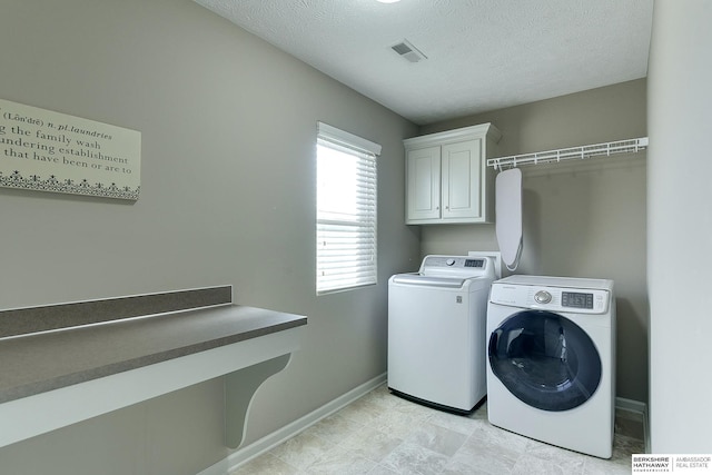 clothes washing area with a textured ceiling, cabinets, and washer and clothes dryer