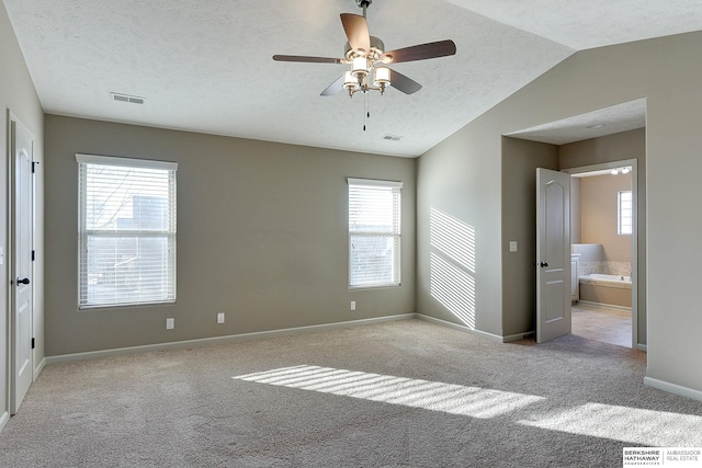 unfurnished bedroom featuring ceiling fan, connected bathroom, light carpet, and lofted ceiling