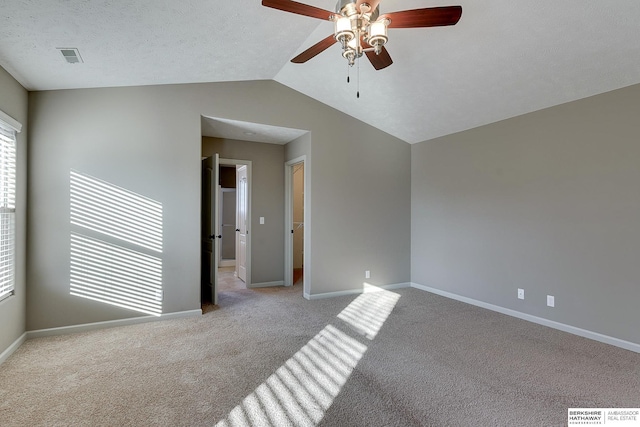 unfurnished room featuring ceiling fan, light colored carpet, a textured ceiling, and vaulted ceiling