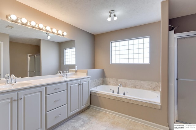 bathroom with a textured ceiling, independent shower and bath, and vanity