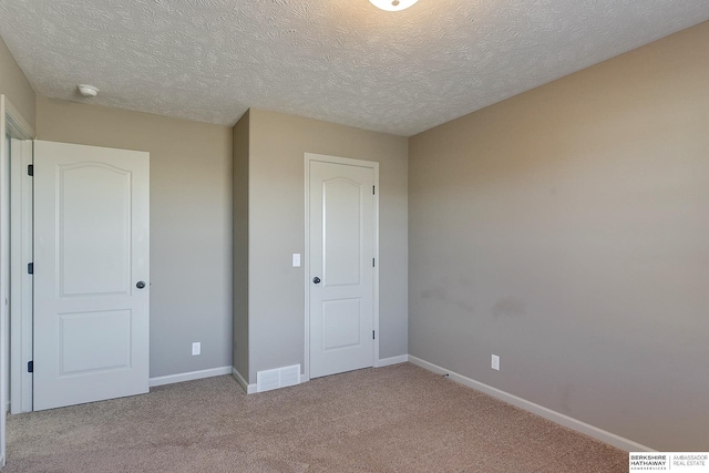 unfurnished bedroom with light colored carpet, a closet, and a textured ceiling