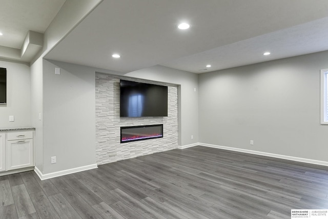 unfurnished living room featuring dark wood-type flooring and a stone fireplace