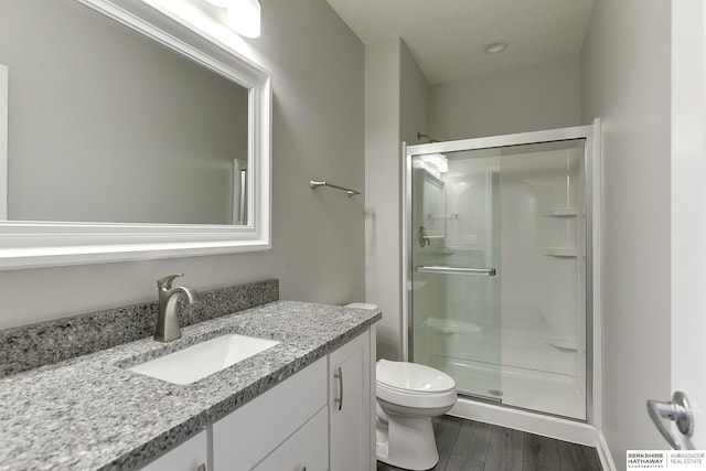 bathroom featuring toilet, vanity, and a shower with shower door