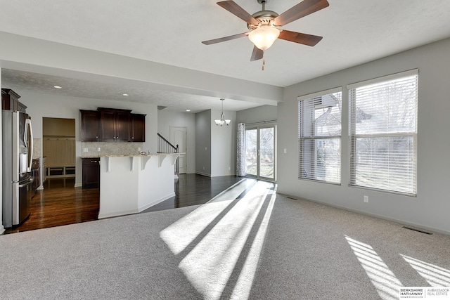 kitchen featuring dark carpet, an island with sink, a breakfast bar area, tasteful backsplash, and stainless steel refrigerator