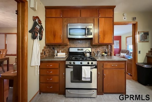 kitchen with decorative backsplash, light tile patterned floors, and appliances with stainless steel finishes