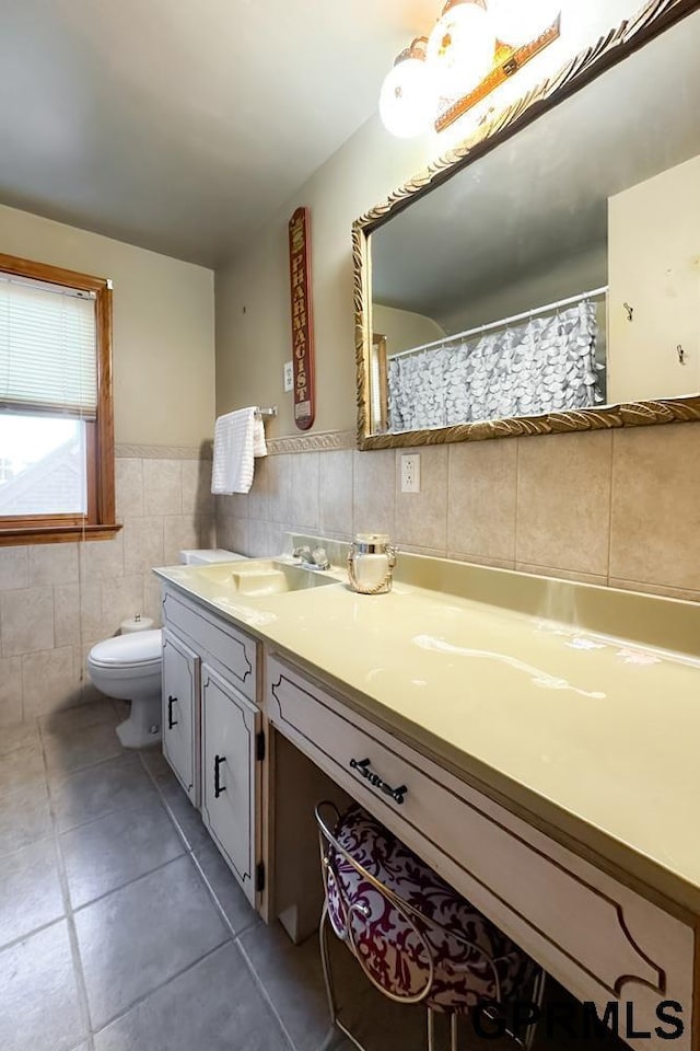 bathroom featuring toilet, vanity, tile walls, and tile patterned floors